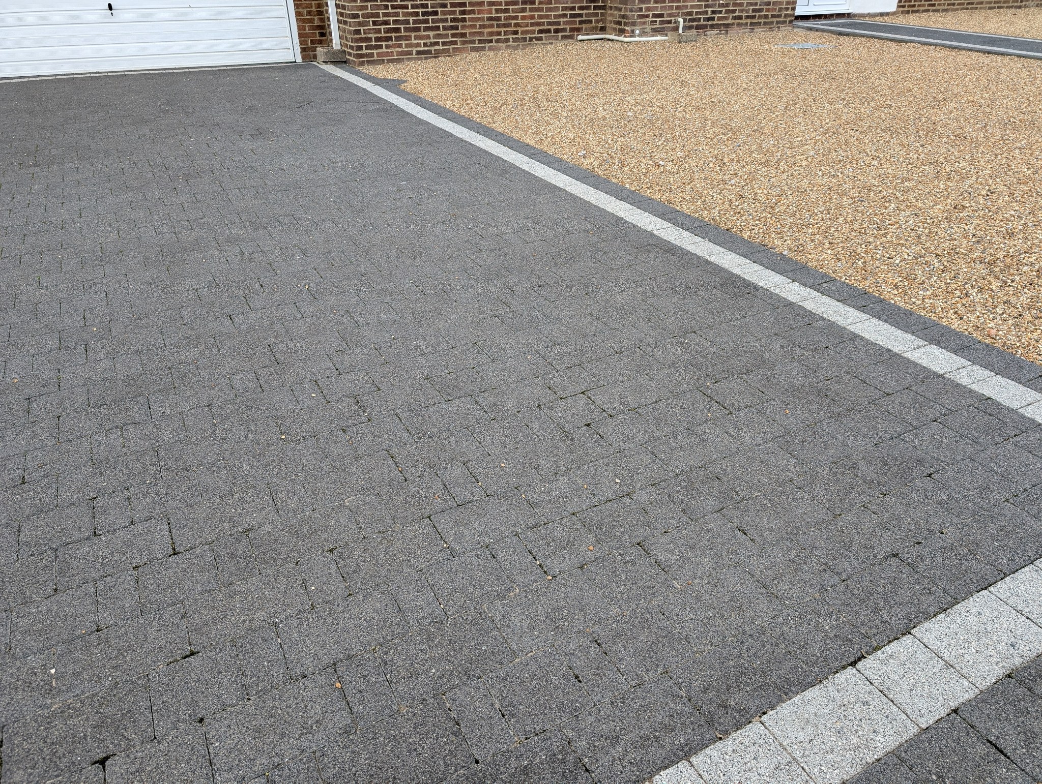 Grey block-paved driveway with gravel border