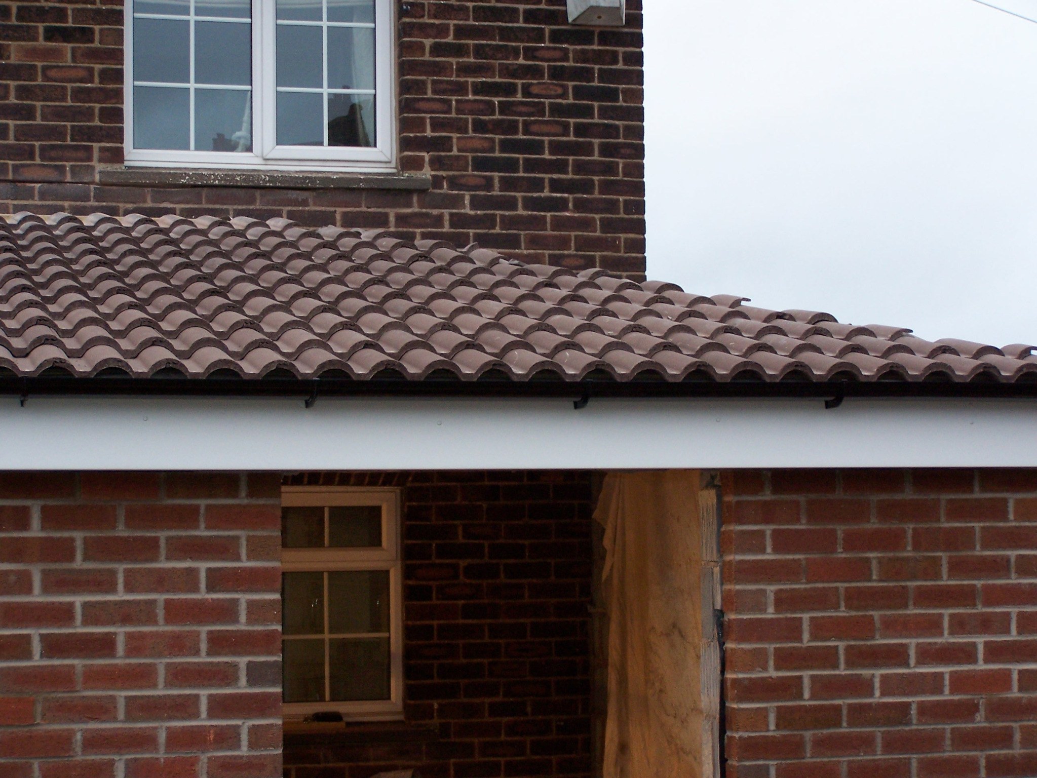 Brick house extension with tiled roof and white fascia