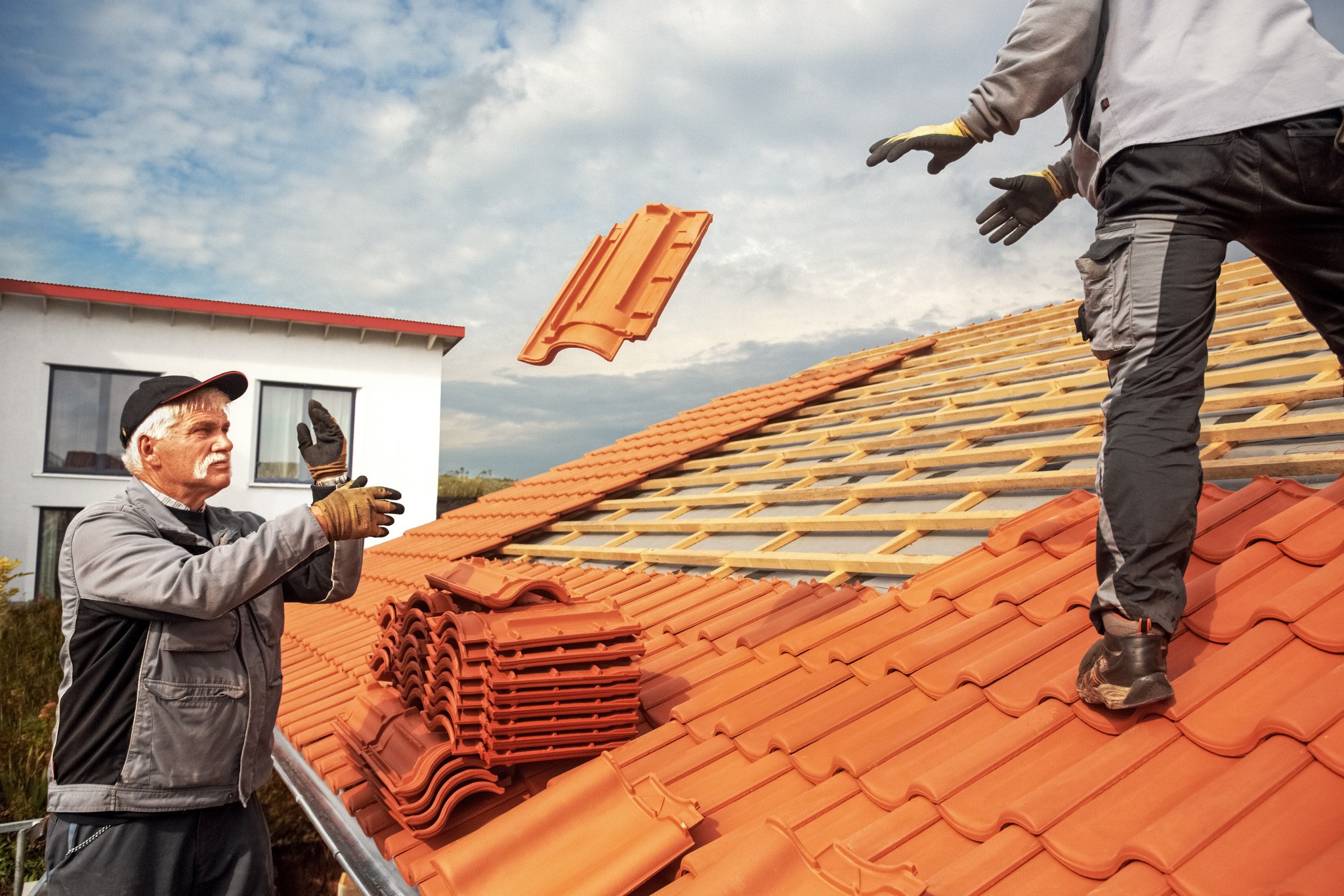 Roofers working with clay roof tiles